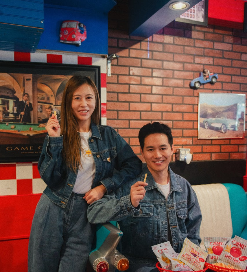 Two people sitting on a vintage scooter in a retro-themed room with brick walls and arcade games.
