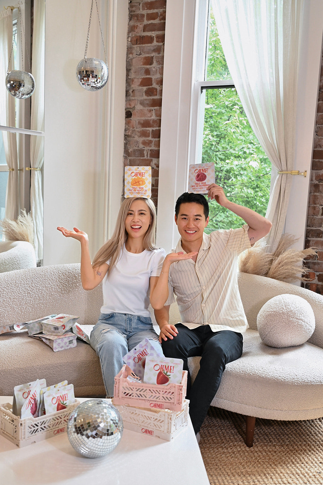 Two people sitting on a couch in a living room with products and packaging.