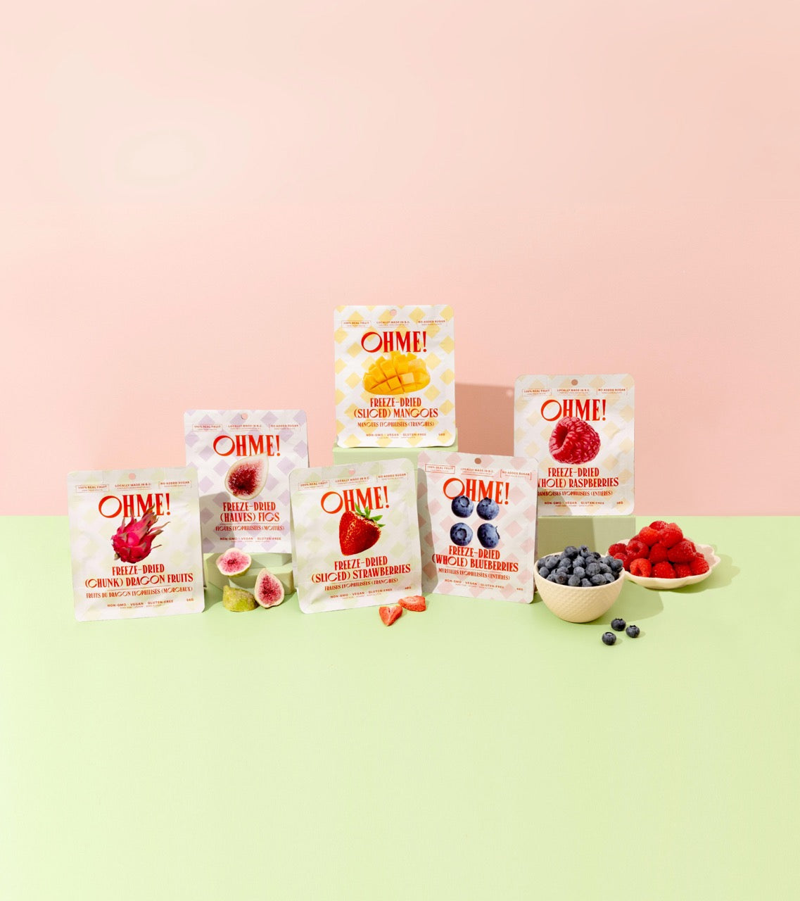 Assorted Ohme! fruit pouches on a pink and green gradient background