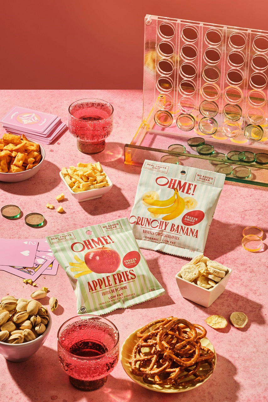 Snack platter with OMLM! Apple Fries, Crunchy Banana, and other snacks on a pink background.